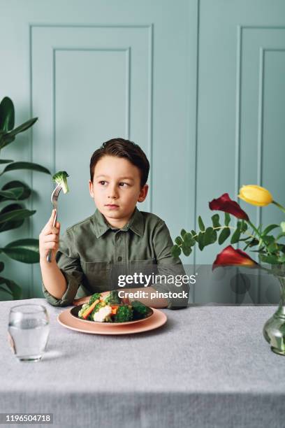 child is very unhappy with having to eat vegetables. there is a lot of vegetables on his plate. he hates vegetables. - hate broccoli stock pictures, royalty-free photos & images