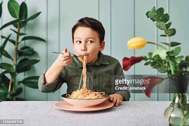 6-7 jahre alt süßes kind essen spaghetti. er ist glücklich. - boys only caucasian ethnicity 6 7 years stock-fotos und bilder