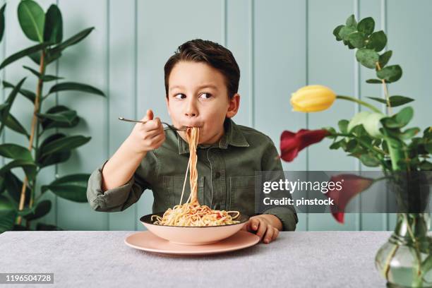 6-7 years old cute child eating spaghetti. he is happy. - 6 7 years stock pictures, royalty-free photos & images