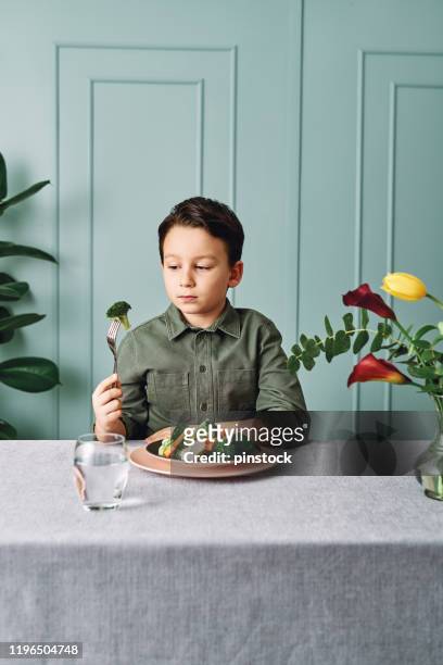 child is very unhappy with having to eat vegetables. there is a lot of vegetables on his plate. he hates vegetables. - hate broccoli stock pictures, royalty-free photos & images