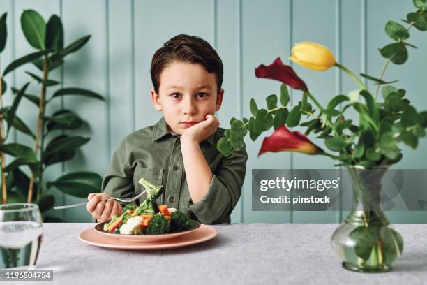 child is very unhappy with having to eat vegetables. there is a lot of vegetables on his plate. he hates vegetables. - hate broccoli stock pictures, royalty-free photos & images