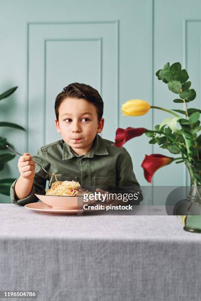 6-7 jahre alt süßes kind essen spaghetti. er ist glücklich. - boys only caucasian ethnicity 6 7 years stock-fotos und bilder