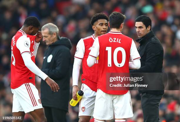 Mikel Arteta, Manager of Arsenal speaks with Mesut Ozil and Reiss Nelson during the Premier League match between Arsenal FC and Chelsea FC at...