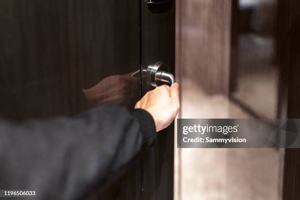 a young man is opening a door using a room key - hotel tür stock-fotos und bilder
