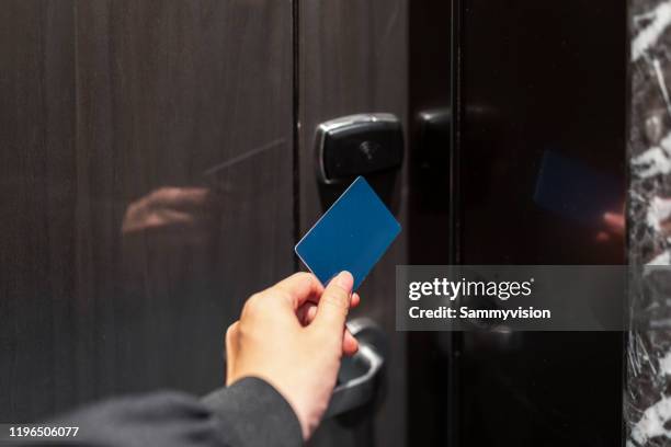 a young man is opening a door using a room key - hotelzimmer tür stock-fotos und bilder