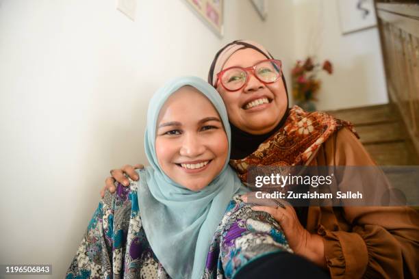 indonesian senior woman with daughter in hijab taking selfie  at home - malaysia batik stock pictures, royalty-free photos & images