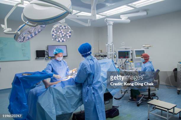 surgeon team operating. surgical lights shining on medical team performing operation on patient - heart surgery stock pictures, royalty-free photos & images
