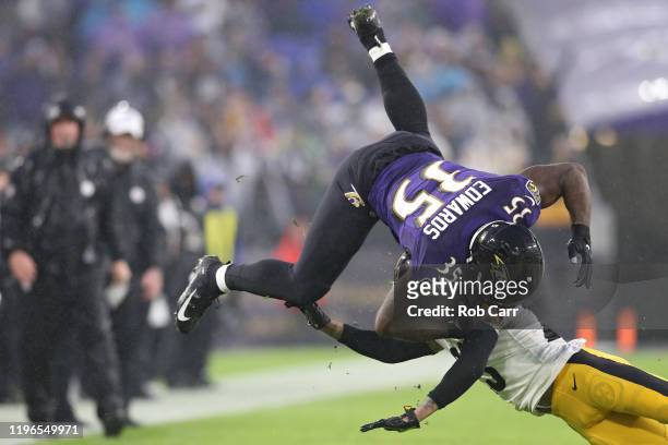 Running back Gus Edwards of the Baltimore Ravens is tackled by cornerback Joe Haden of the Pittsburgh Steelers during the first quarter at M&T Bank...