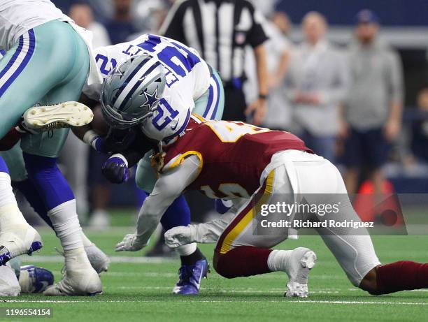Ezekiel Elliott of the Dallas Cowboys is hit by Maurice Smith of the Washington Redskins in the first quarter at AT&T Stadium on December 29, 2019 in...