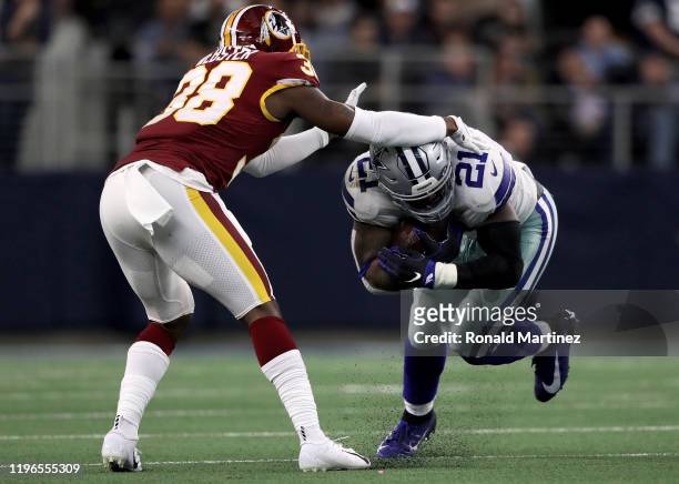 Ezekiel Elliott of the Dallas Cowboys runs with the ball while being tackled by Kayvon Webster of the Washington Redskins in the second quarter in...