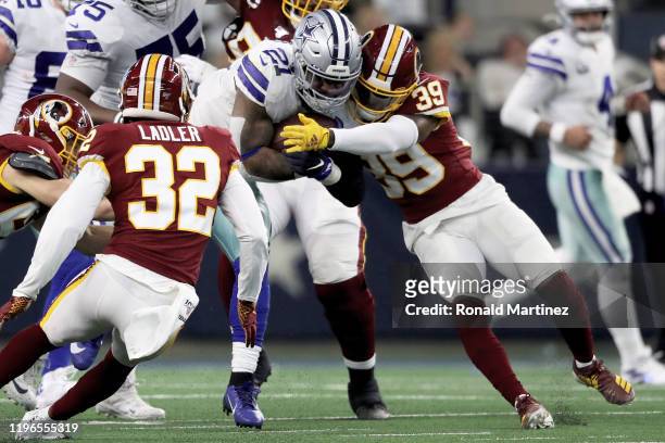 Ezekiel Elliott of the Dallas Cowboys runs with the ball while being tackled by Jeremy Reaves of the Washington Redskins in the second quarter in the...
