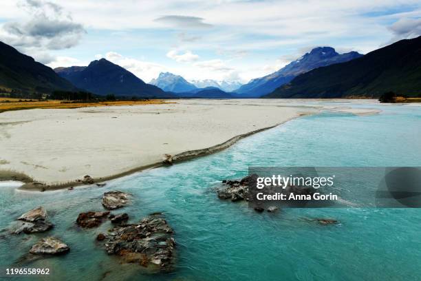 turquoise-colored dart river with snowcapped southern alps on horizon on summer afternoon, glenorchy, south island, new zealand - dart river new zealand stock pictures, royalty-free photos & images
