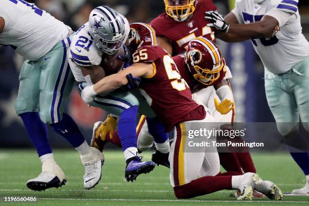 Ezekiel Elliott of the Dallas Cowboys runs with the ball while being tackled by Cole Holcomb of the Washington Redskins in the second quarter in the...