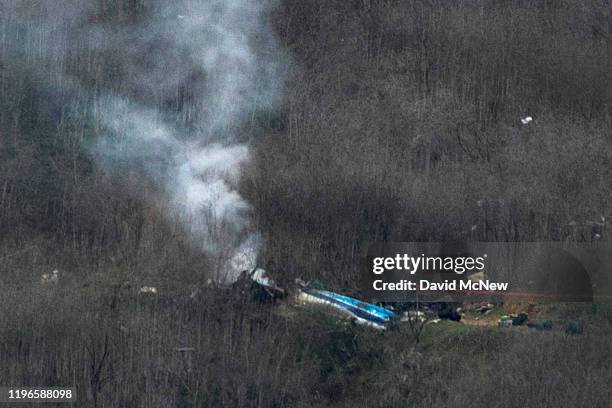 Wreckage of the crashed helicopter that was carrying former NBA star Kobe Bryant and his 13-year-old daughter Gianna smolders on the ground on...