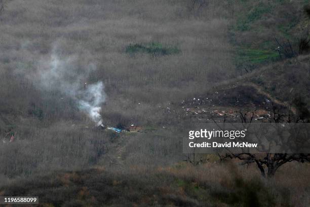 Wreckage of the crashed helicopter that was carrying former NBA star Kobe Bryant and his 13-year-old daughter Gianna smolders on the ground on...