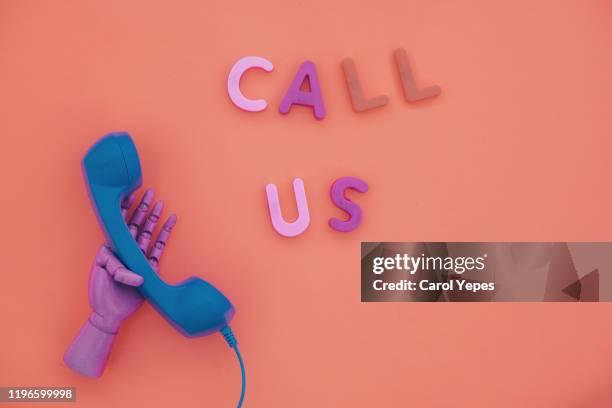 blue telephone receiver and call us message in coral color - belt stockfoto's en -beelden