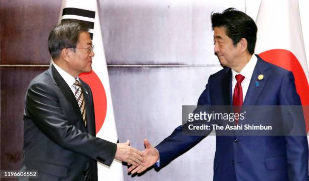 South Korean President Moon Jae-in and Japanese Prime Minister Shinzo Abe shake hands prior to their bilateral meeting on the sidelines of the South...