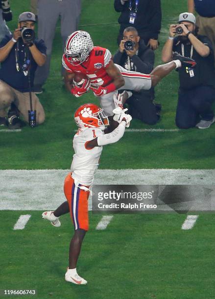 Wide receiver Garrett Wilson of the Ohio State Buckeyes leaps to catch a pass over defensive back Derion Kendrick of the Clemson Tigers during the...