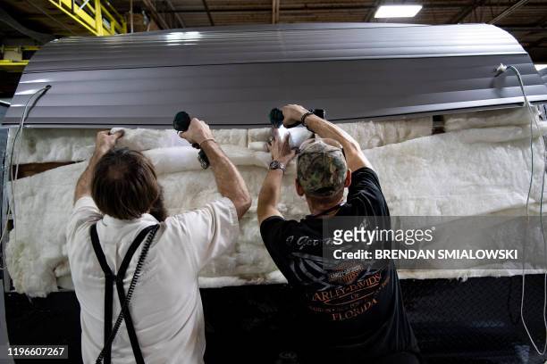 Workers remove scratched metal during inspection while assembling a camping trailer at Riverside RV, builders of recreational vehicles, on January...