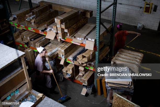 Workers sweep the floor at Riverside RV, builders of recreational vehicles, on January 24, 2020 in LaGrange, Indiana. - The six or seven vehicles...