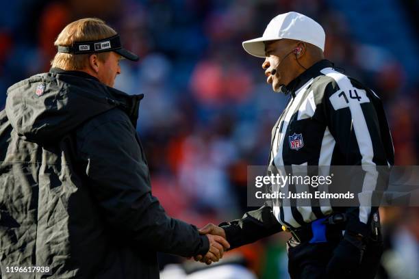 Head coach Jon Gruden of the Oakland Raiders shake hands with referee Shawn Smith before the game against the Denver Broncos at Empower Field at Mile...