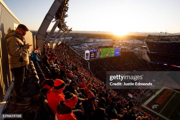 General view of the stadium as a fan uses his phone while the Denver Broncos drive against the Oakland Raiders while the sun sets during the third...