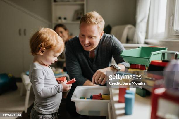 father watching son play with toy blocks in living room - baby bath toys stock-fotos und bilder