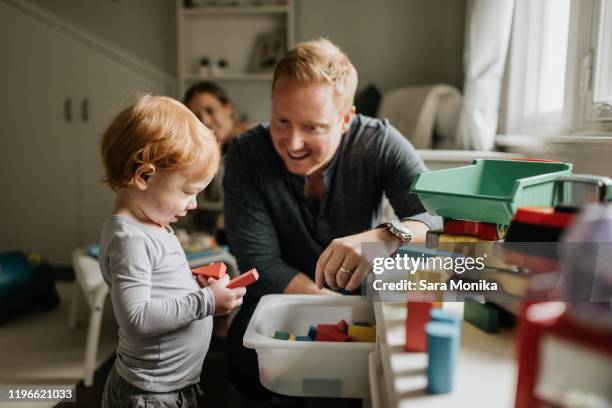 father watching son play with toy blocks in living room - child playing in room stockfoto's en -beelden