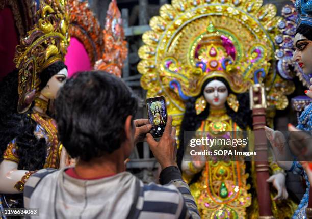 Man taking pictures of Devi Saraswati idol on his phone during the preparations for the festival. Basant Panchami or Vasant Panchami is a Hindu...