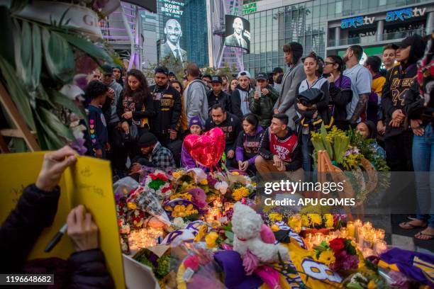 People gather around a makeshift memorial for former NBA and Los Angeles Lakers player Kobe Bryant after learning of his death, at LA Live plaza in...