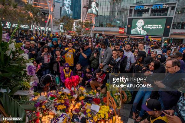 People gather around a makeshift memorial for former NBA and Los Angeles Lakers player Kobe Bryant after learning of his death, at LA Live plaza in...