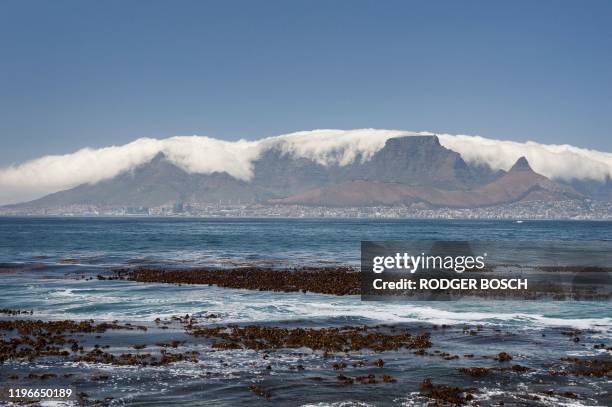 View of Table Mountain, covered with clouds and the city of Cape Town below, taken from Robben Island, where Nelson Mandela, an anti-apartheid...