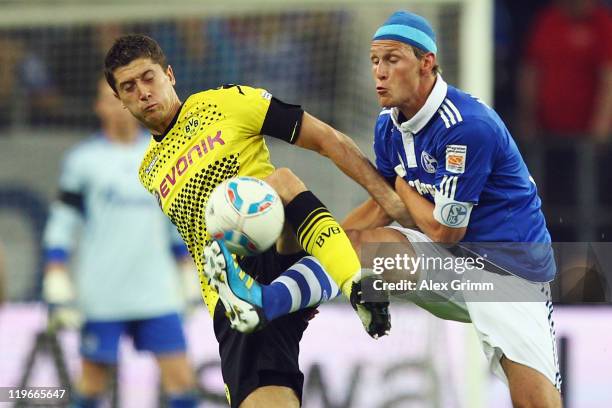 Robert Lewandowski of Dortmund is challenged by Benedikt Hoewedes of Schalke during the Supercup match between FC Schalke 04 and Borussia Dortmund at...