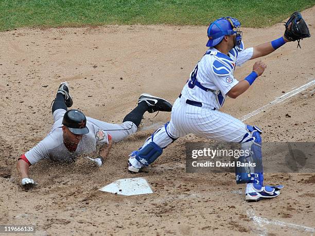Geovany Soto of the Chicago Cubs can't make a tag on Angel Sanchez of the Houston Astros at home plate on July 23, 2011 at Wrigley Field in Chicago,...