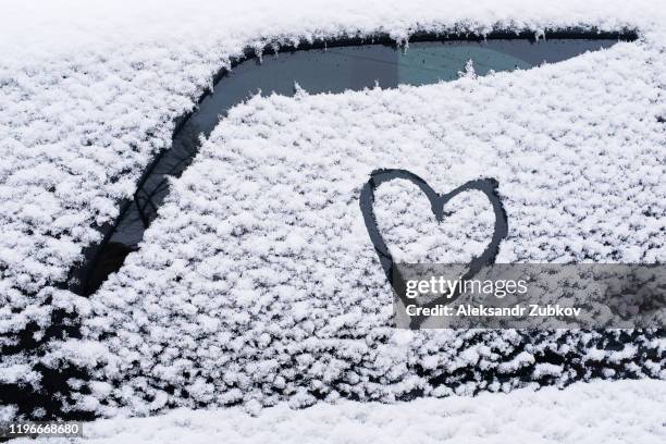 the heart is painted on the glass of the car, on the background of snow. symbol of love, romance, valentine's day. - snow melting on car stock pictures, royalty-free photos & images