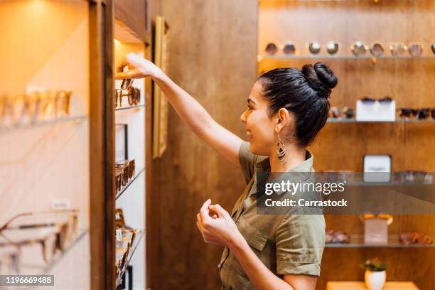 beautiful woman in optics store trying on glasses. - taking off glasses stock pictures, royalty-free photos & images
