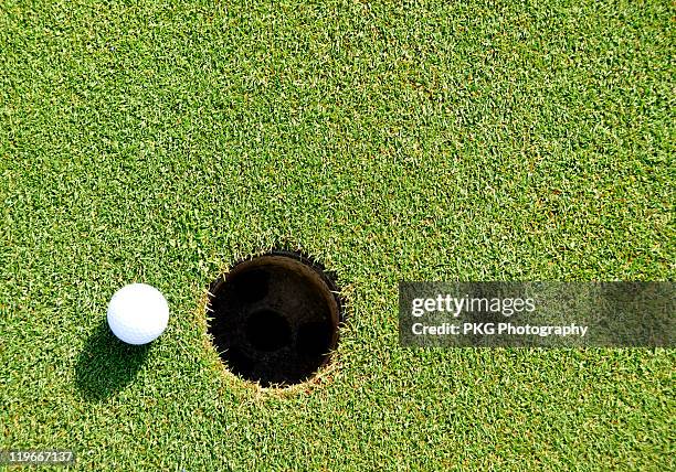 ball and hole - golf ball hole stock pictures, royalty-free photos & images