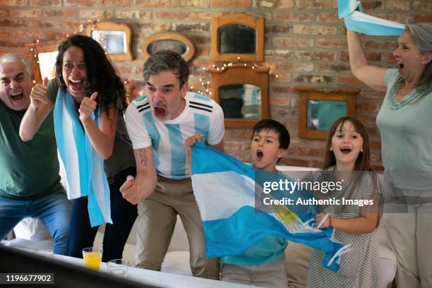 argentinische familie fußballfans fröhlich, schreien essen zum ende pizza und suchen fußball spielen - argentina friendly match stock-fotos und bilder