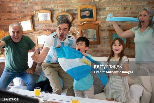 argentinska familjen fotbollsfans glad, skrikande äta takeaway pizza och söker fotboll spela - argentinsk kultur bildbanksfoton och bilder