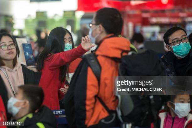Travellers and staff members, wearing masks, stand at the checking area for flights to Shangai at the Vaclav Havel International Airport on January...