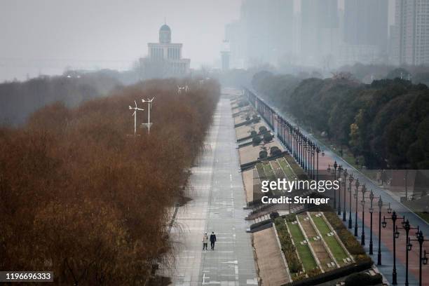 Two residents walk in an empty Jiangtan park on January 27, 2020 in Wuhan, China. As the death toll from the coronavirus reaches 80 in China with...