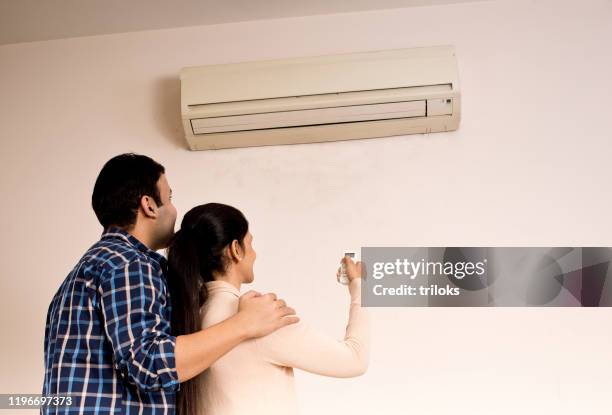 stel de temperatuur van de airconditioner aanpassen met behulp van de afstandsbediening - hot wife stockfoto's en -beelden