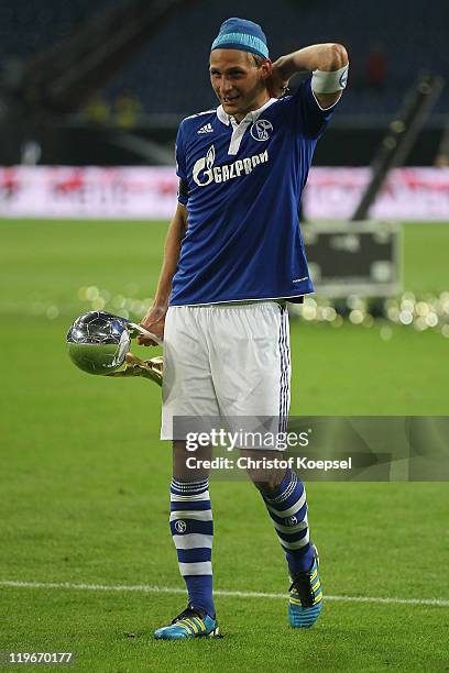 Benedikt Hoewedes of Schalke holds the Supercup trophy after winning the Supercup match between FC Schalke 04 and Borussia Dortmund at Veltins Arena...