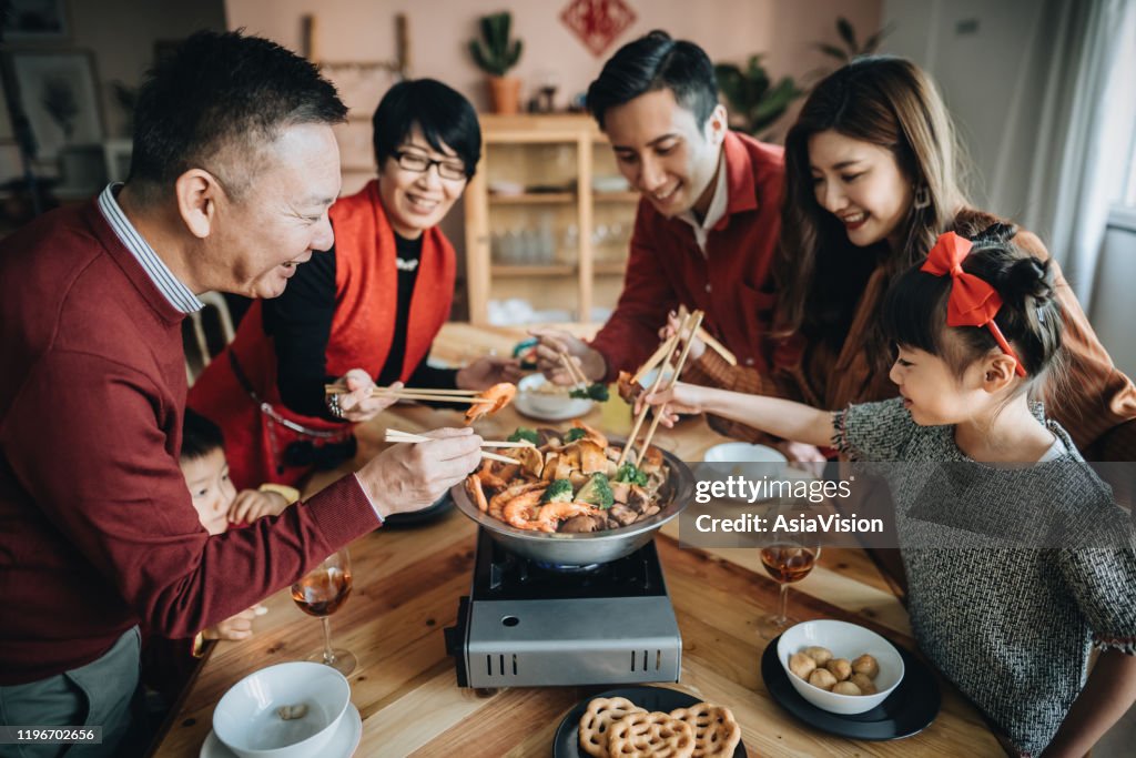 Drei Generationen von fröhlichen asiatischen Familie feiern chinesisches Neujahr und genießen traditionelle chinesische Poon Choi auf Wiedersehen Abendessen