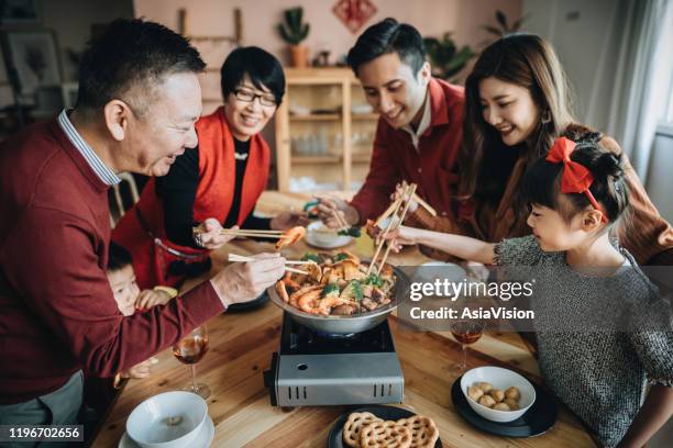 trois générations de famille asiatique joyeuse célébrant le nouvel an chinois et appréciant le choi chinois traditionnel de poon sur le dîner de retrouvailles - chinese new year food photos et images de collection