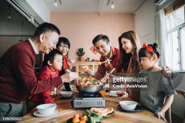 trois générations de joyeuses familles asiatiques célèbrent le nouvel an chinois et dégustent le poon choi chinois traditionnel lors d’un dîner de retrouvailles - chinese new year food photos et images de collection