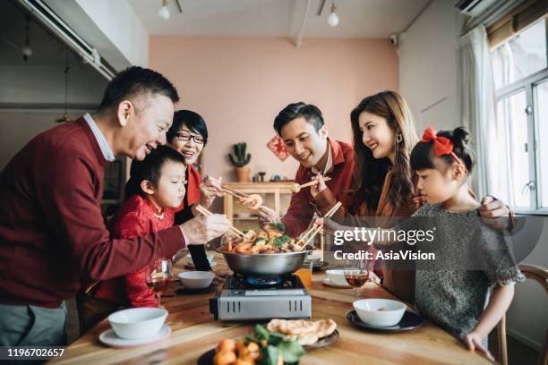 trois générations de joyeuses familles asiatiques célèbrent le nouvel an chinois et dégustent le poon choi chinois traditionnel lors d’un dîner de retrouvailles - china family photos et images de collection