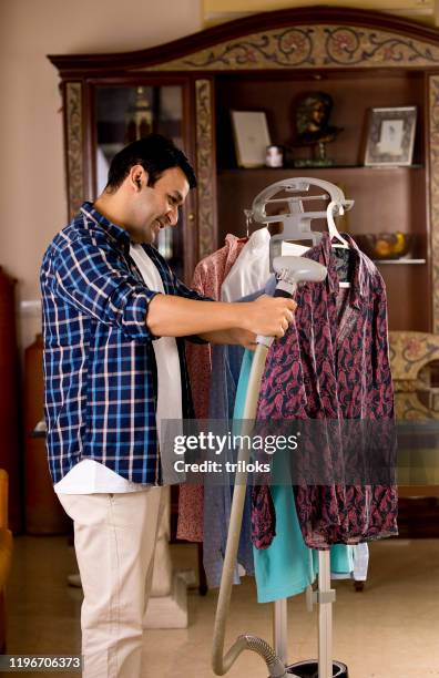 man using garment steamer on shirt - iron stock pictures, royalty-free photos & images