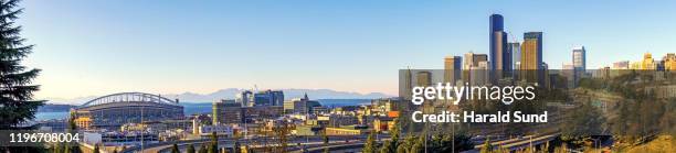 daytime panoramic view of the modern urban down town seattle skyline with office towers, skyscrapers, freeways, sports stadium, the seattle great wheel, puget sound and the olympic mountains in the distance. - puget sound stock pictures, royalty-free photos & images