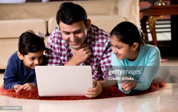 vater und kinder mit laptop im wohnzimmer zu hause - indian living room stock-fotos und bilder